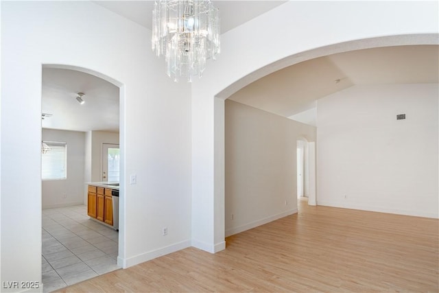 4507 Golden Palomino Ln, North Las Vegas, NV 89032 - unfurnished room with arched walkways, light wood finished floors, vaulted ceiling, a chandelier, and baseboards