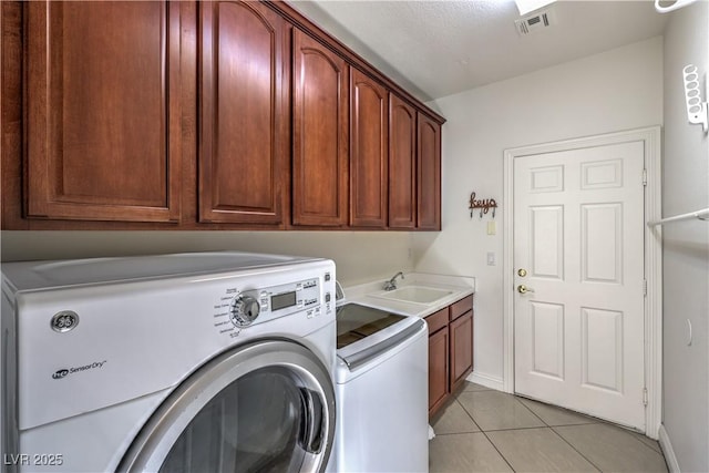 laundry area featuring cabinets, separate washer and dryer, sink, and light tile patterned floors