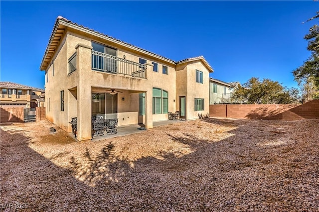 back of property featuring ceiling fan, a balcony, and a patio