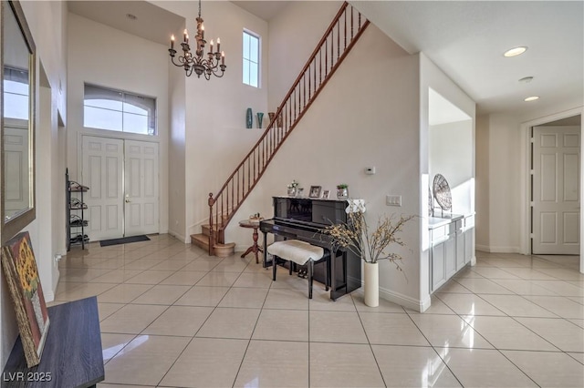 tiled foyer entrance with a high ceiling, plenty of natural light, and a chandelier