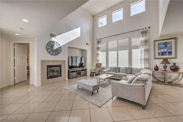 living room with light tile patterned floors, a towering ceiling, and a fireplace