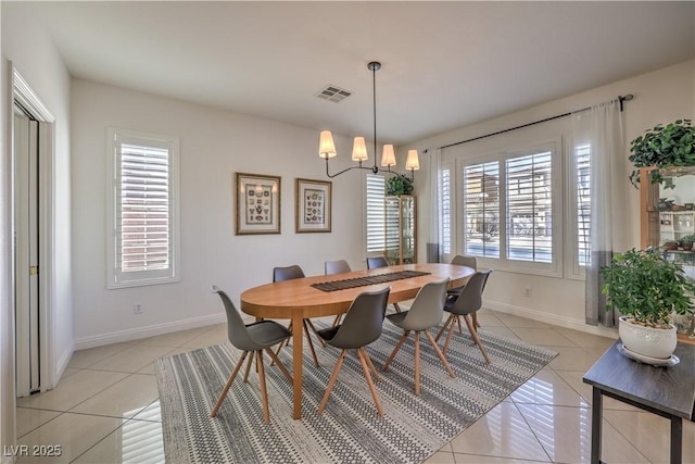 dining area with light tile patterned floors and an inviting chandelier