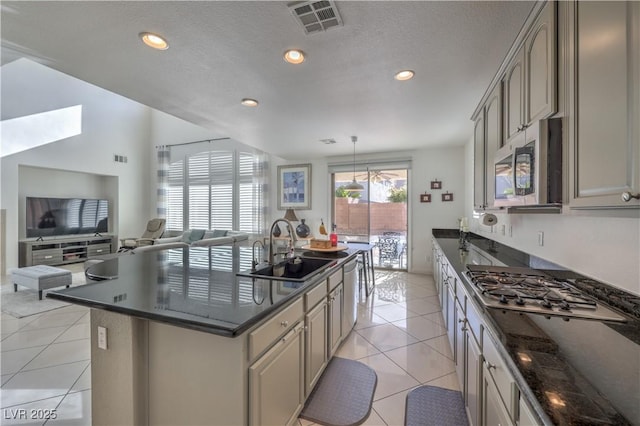 kitchen featuring sink, appliances with stainless steel finishes, hanging light fixtures, a center island, and light tile patterned flooring