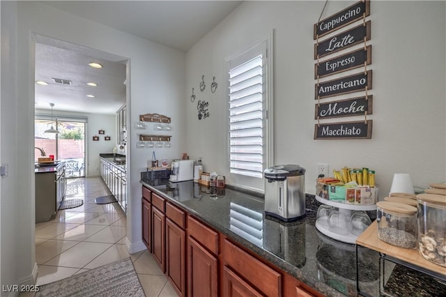 bar with dark stone countertops and light tile patterned floors