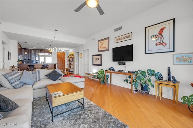 living room with ceiling fan with notable chandelier and wood-type flooring