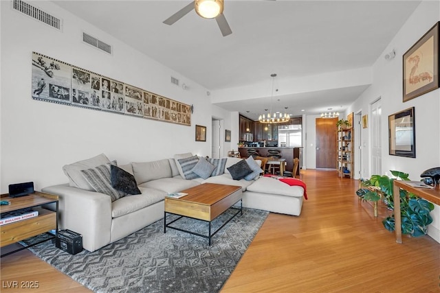 living room featuring ceiling fan with notable chandelier and wood-type flooring