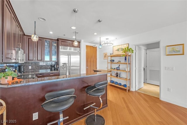 kitchen featuring pendant lighting, stainless steel appliances, a breakfast bar area, and dark stone counters