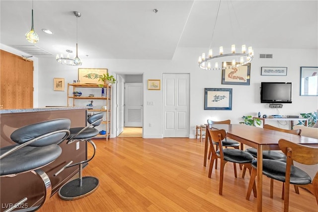 dining area with light hardwood / wood-style flooring and a notable chandelier