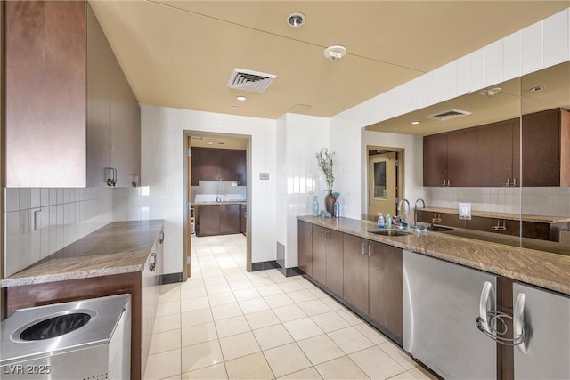 kitchen with tasteful backsplash, sink, light tile patterned floors, and dark brown cabinetry