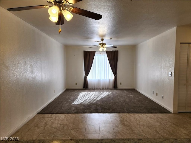 empty room with ceiling fan, carpet floors, and a textured ceiling