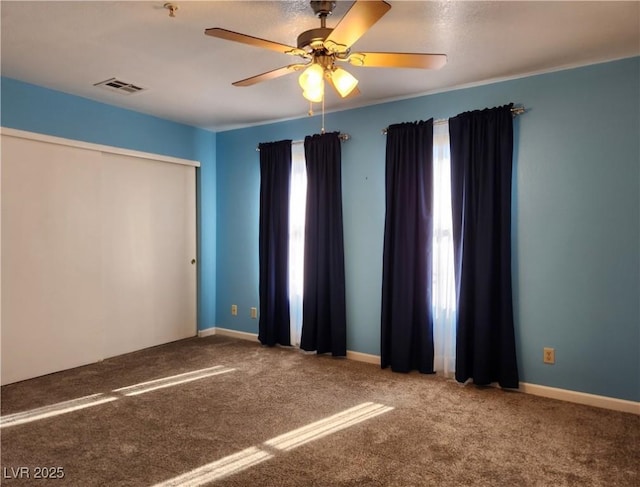 empty room with carpet floors, a wealth of natural light, and ceiling fan