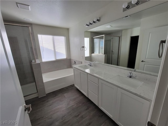 bathroom featuring plus walk in shower, wood-type flooring, and vanity