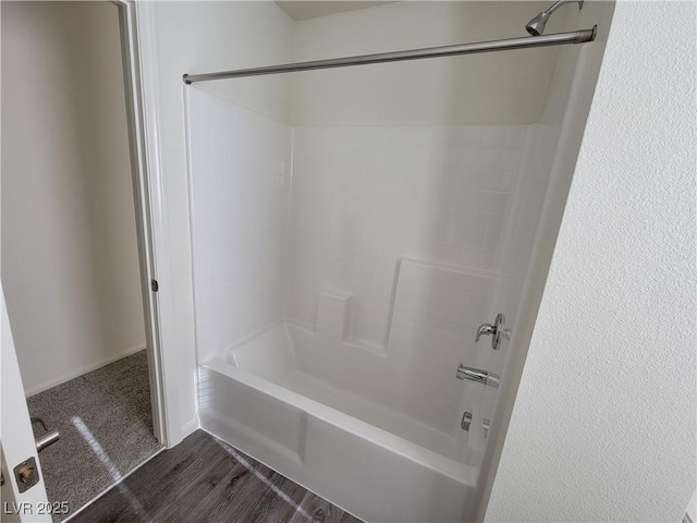 bathroom with hardwood / wood-style flooring and shower / washtub combination