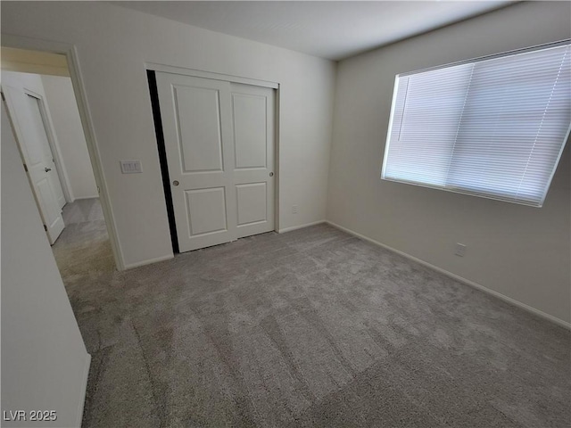 unfurnished bedroom with light colored carpet and a closet