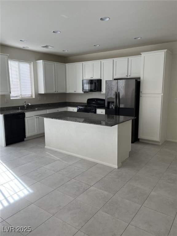 kitchen with white cabinetry, a kitchen island, light tile patterned floors, and black appliances