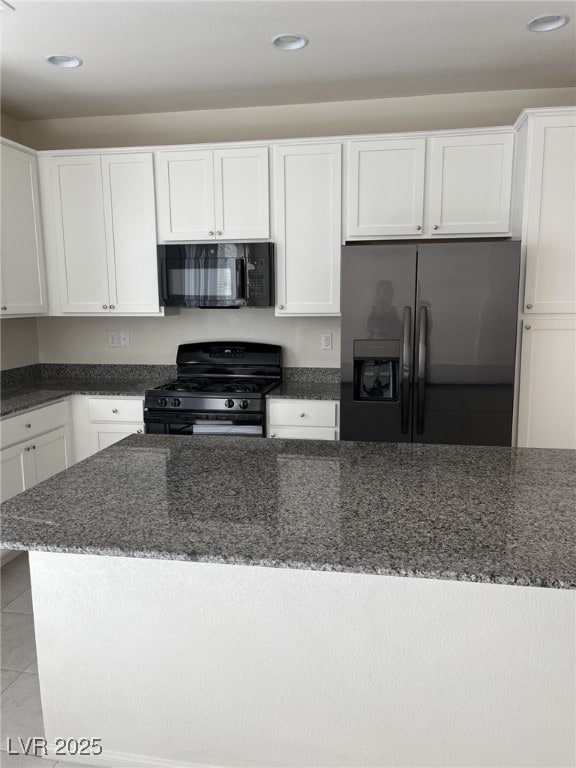 kitchen featuring light tile patterned flooring, white cabinets, dark stone counters, and black appliances