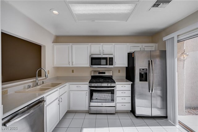 kitchen with sink, light tile patterned flooring, white cabinets, and appliances with stainless steel finishes