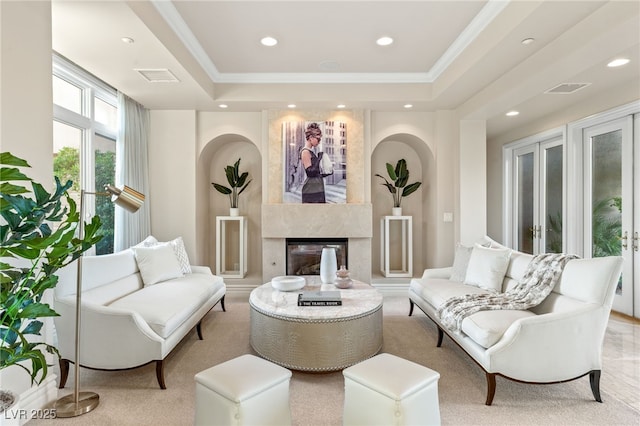 living room featuring french doors, a premium fireplace, ornamental molding, and a tray ceiling