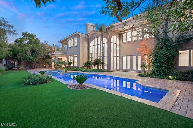 view of swimming pool featuring an in ground hot tub, a patio area, and a lawn