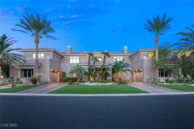 1549 Foothills Village Dr, Henderson, NV 89012 - view of front of home featuring a garage, stone siding, stucco siding, a chimney, and driveway