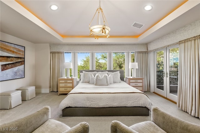 bedroom with light colored carpet, a tray ceiling, and access to outside