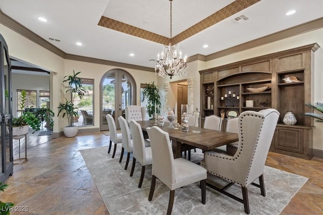 dining area with a raised ceiling, crown molding, french doors, and a chandelier