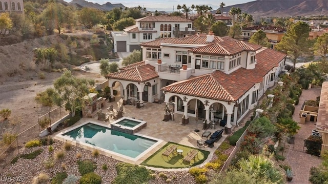 back of property featuring an in ground hot tub, a balcony, and a patio