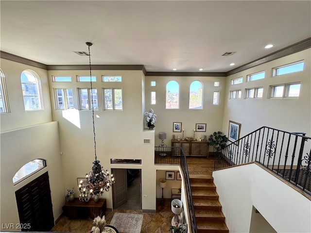 living room with an inviting chandelier, ornamental molding, and a high ceiling