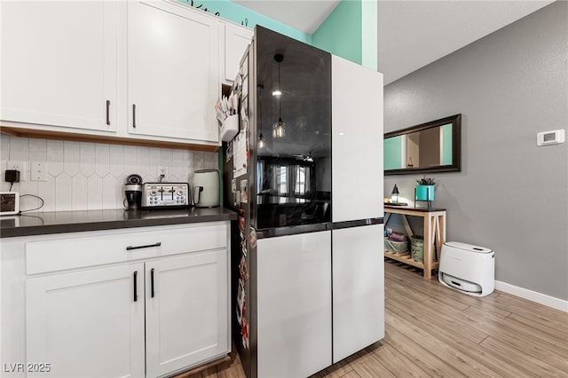 kitchen with white cabinetry, tasteful backsplash, refrigerator, and light hardwood / wood-style flooring