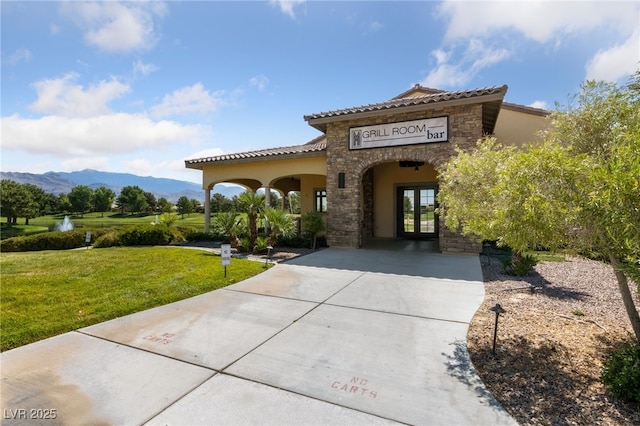 exterior space with french doors, a mountain view, and a front yard