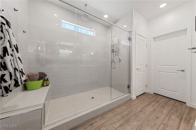 bathroom with wood-type flooring and a shower with shower door