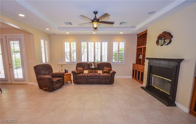 living room featuring light tile patterned floors, a raised ceiling, and a healthy amount of sunlight