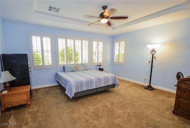 carpeted bedroom with ceiling fan and a tray ceiling