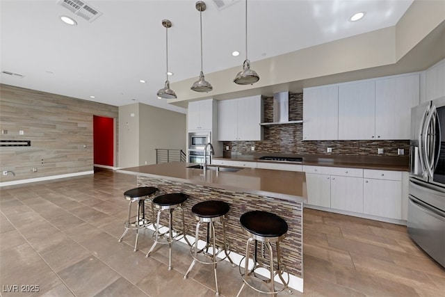 kitchen featuring appliances with stainless steel finishes, a breakfast bar, decorative light fixtures, white cabinetry, and sink