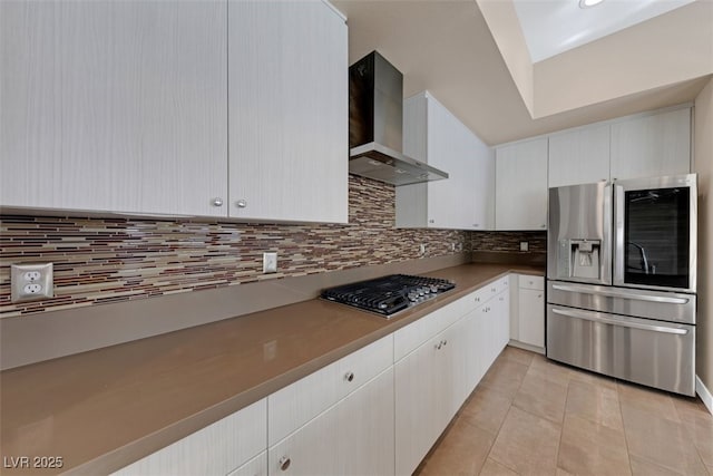 kitchen featuring white cabinets, appliances with stainless steel finishes, light tile patterned floors, and wall chimney range hood