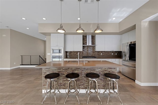 kitchen featuring wall chimney exhaust hood, white cabinetry, appliances with stainless steel finishes, and sink