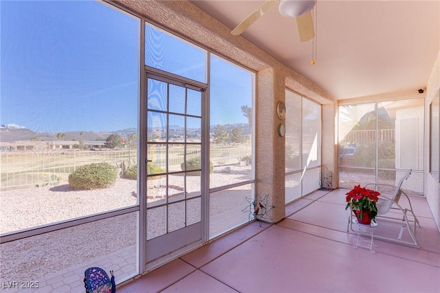 unfurnished sunroom featuring a mountain view and ceiling fan