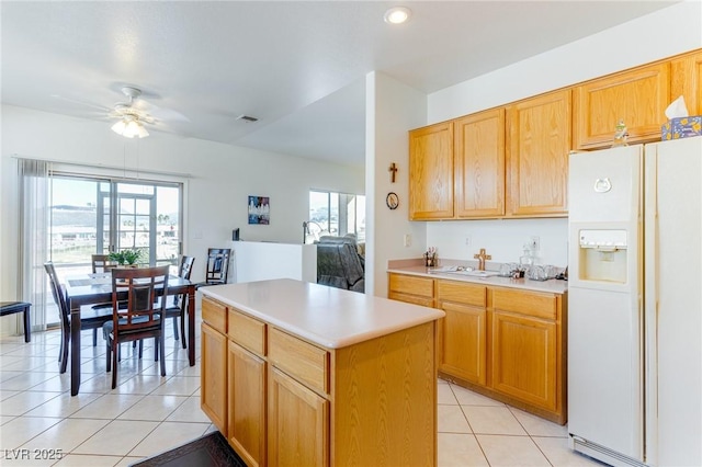 kitchen with light tile patterned flooring, a center island, white fridge with ice dispenser, and sink