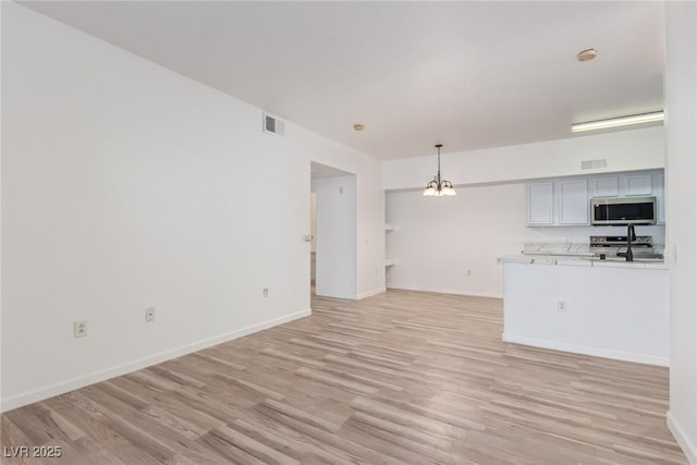 unfurnished living room featuring a notable chandelier and light hardwood / wood-style floors