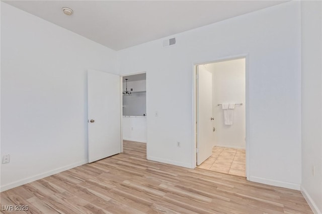 unfurnished bedroom with a spacious closet, connected bathroom, light wood-type flooring, and a closet