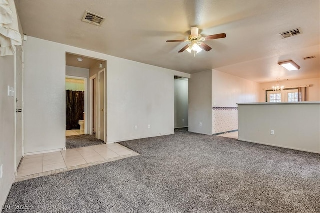 carpeted empty room featuring ceiling fan with notable chandelier