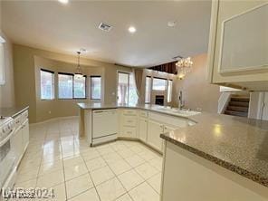 kitchen featuring sink, light tile patterned floors, dishwasher, light stone counters, and white cabinets