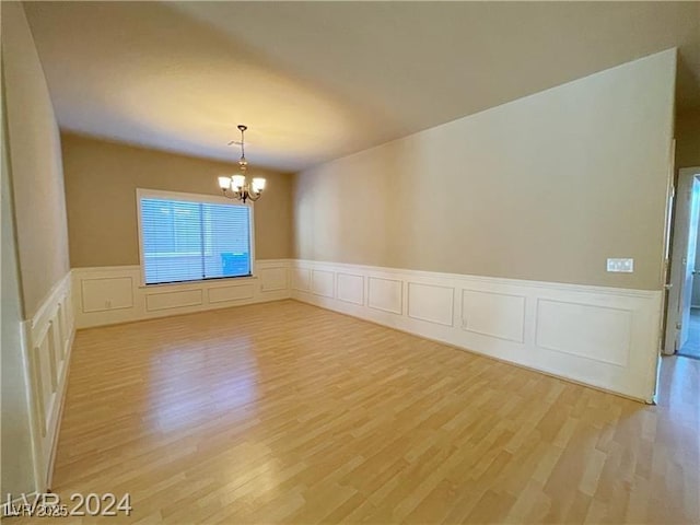 empty room with a chandelier and light hardwood / wood-style floors