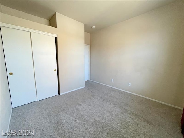 unfurnished bedroom with light colored carpet and a closet