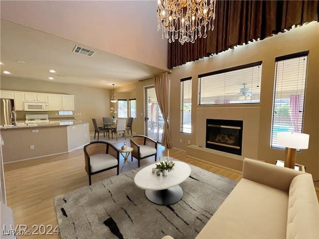 living area featuring recessed lighting, a chandelier, light wood-style floors, visible vents, and a fireplace