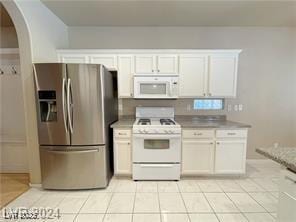 kitchen with arched walkways, white cabinetry, light tile patterned flooring, and white appliances