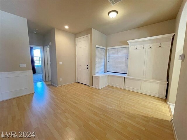 interior space with a wainscoted wall, visible vents, and light wood-style flooring