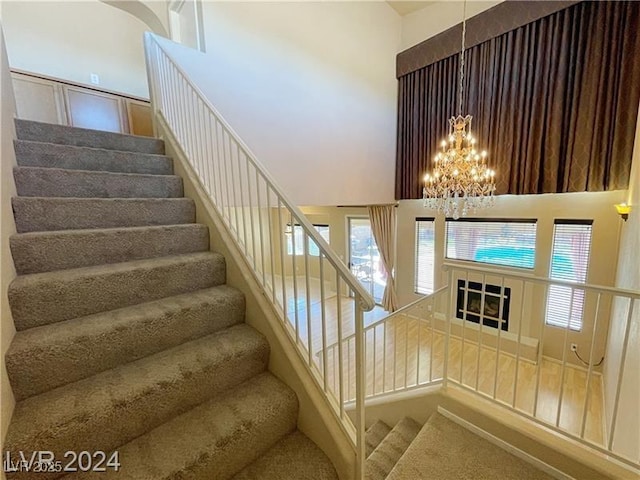 staircase with a towering ceiling and a chandelier