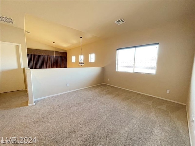 carpeted empty room featuring baseboards, vaulted ceiling, and visible vents