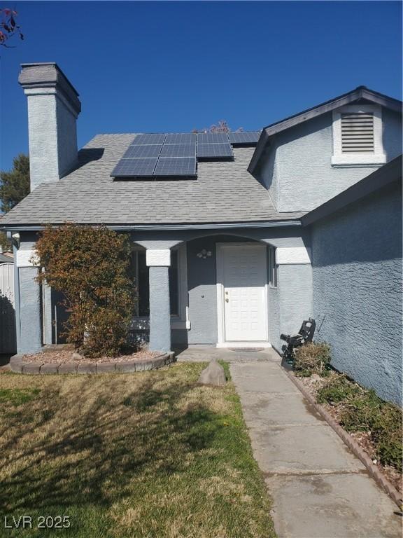 entrance to property featuring a lawn and solar panels